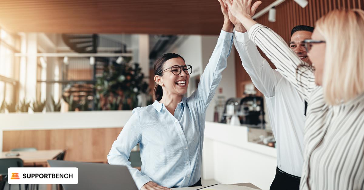 Two team members in a call center celebrate with a high five, showcasing the positive impact of Emotional Intelligence on well-being